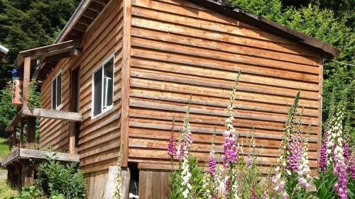 a wooden cabin with flowers in front of it at Hollis Creek Cabin in Hollis