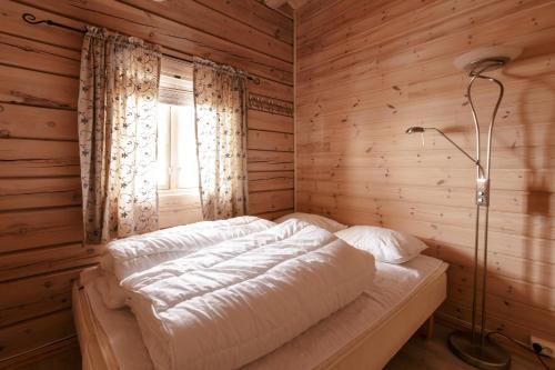 a bed in a wooden room with a window at Røde Kors in Brunstad