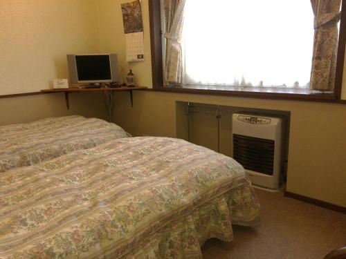 a bedroom with two beds and a window and a television at Shikino Yado Subaru in Chino
