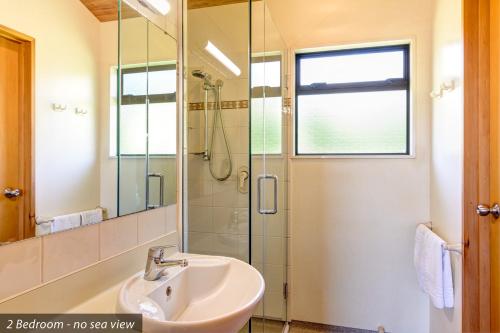 a bathroom with a shower, sink, and mirror at Kaiteri Motels and Apartments in Kaiteriteri