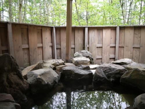 a wooden fence with rocks in front of a body of water at Shikino Yado Subaru in Chino