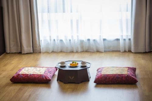 a room with a table and two ottomans at Gloucester Hotel Jeju in Jeju