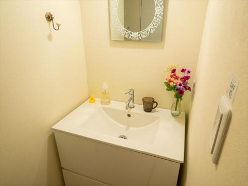 a bathroom with a sink and a mirror and flowers at COTO Tokyo Shibuya 3 in Tokyo
