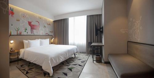 a hotel room with a bed and a chair at ARTOTEL Yogyakarta in Yogyakarta