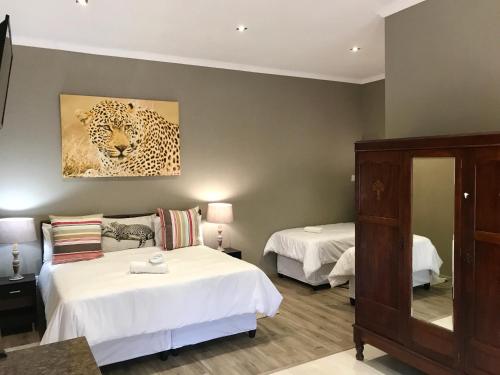 a bedroom with two beds and a painting of a leopard at Aerotropolis Guest Lodge in Kempton Park