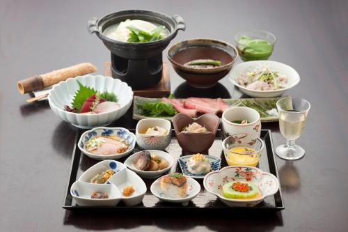 a table with a tray of food and bowls of food at Kusatsu Hotel Bekkan Wata no Yu (Adult Only) in Kusatsu