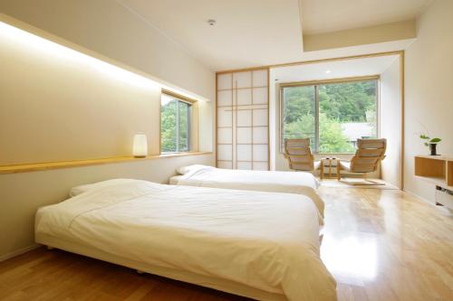 two beds in a room with a table and chairs at Kusatsu Hotel Bekkan Wata no Yu (Adult Only) in Kusatsu