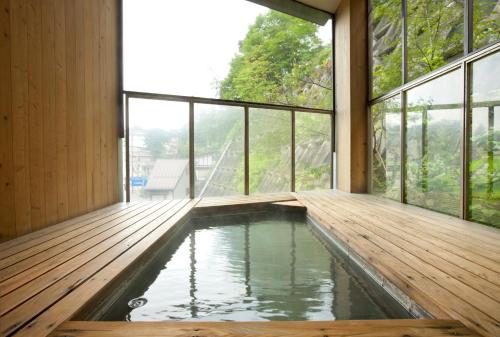 an indoor plunge pool in a house with windows at Kusatsu Hotel Bekkan Wata no Yu (Adult Only) in Kusatsu