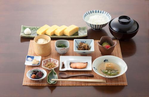 a table topped with bowls and plates of food at Kusatsu Hotel Bekkan Wata no Yu (Adult Only) in Kusatsu