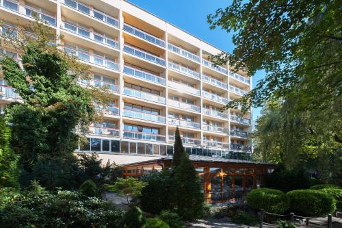 an apartment building with a garden in front of it at Centrum Zdrowia i Wypoczynku Ikar in Kołobrzeg