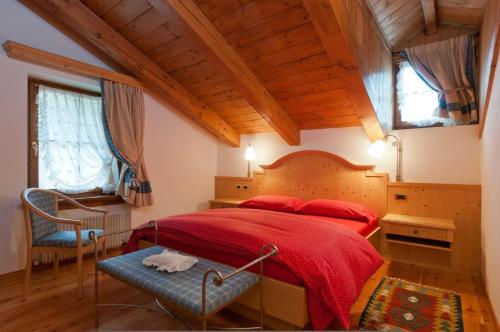 1 dormitorio con 1 cama roja y 1 silla en Appartamenti Royal, en San Vito di Cadore