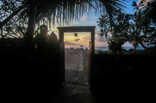 a person standing behind a door with a sunset in the background at Balangan Sea View Bungalow in Jimbaran