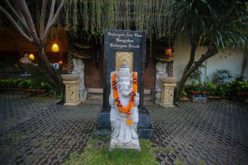 a statue in front of a building with a sign at Balangan Sea View Bungalow in Jimbaran