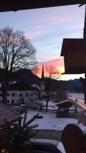 a sunset over a town with a church and snow at Weber´s Fewo in Graswang