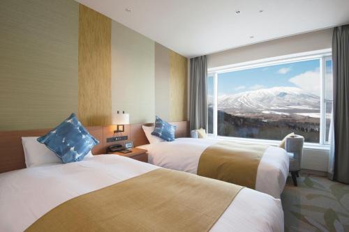 two beds in a hotel room with a mountain view at Shizukuishi Prince Hotel in Shizukuishi
