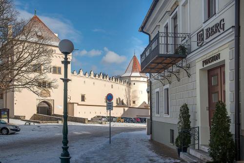 a building with snow on the ground next to a street at Penzión Berg in Kežmarok