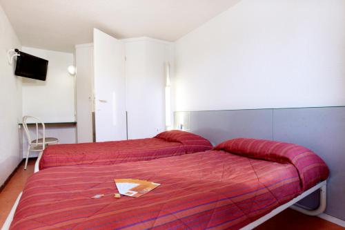 two beds in a bedroom with a red blanket at Hôtel Premiere Classe Pamiers in Pamiers