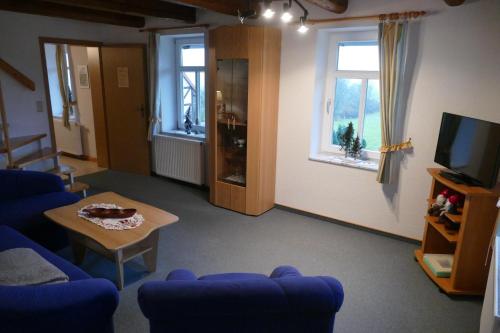 a living room with a couch and a table and two windows at Kutschergasthof Am Sonnenstein in Sonnenstein