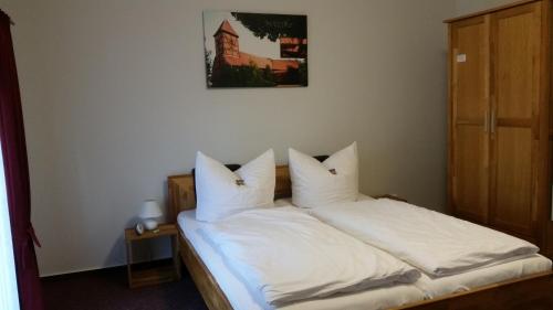 a bedroom with a bed with white sheets and pillows at Pension Am Dorfanger in Hohennauen