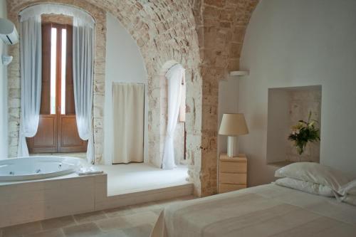 a bedroom with a bed and a tub and a window at Hotel Corte Altavilla in Conversano