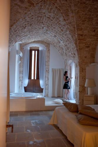 a woman in a room with a bed and a window at Hotel Corte Altavilla in Conversano