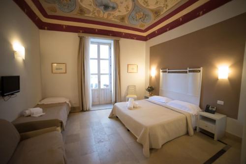 a hotel room with two beds and a couch at Hotel Gargallo in Siracusa