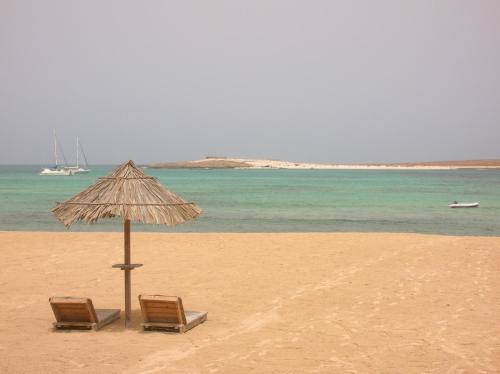 two chairs and an umbrella on a beach at Oasis Palmeira in Santa Maria