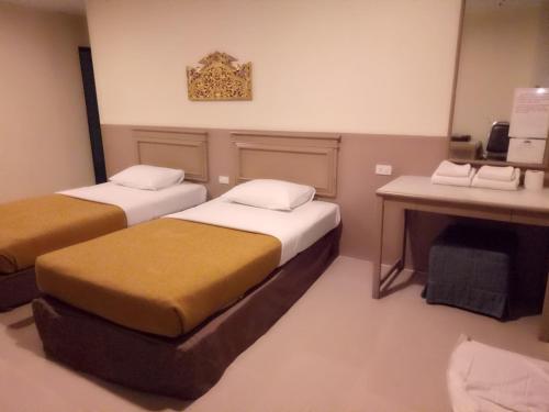 a hotel room with two beds and a desk at Tongpoon Hotel in Bangkok
