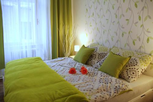 a bed with green pillows and two tomatoes on it at Comfortable apartments under the St. Barbara´s Cathedral in Kutná Hora