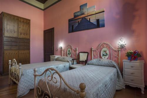 ヴィテルボにあるAl Ponte Levatoio Pianoscaranoのピンクの壁のベッドルーム1室(ベッド2台付)