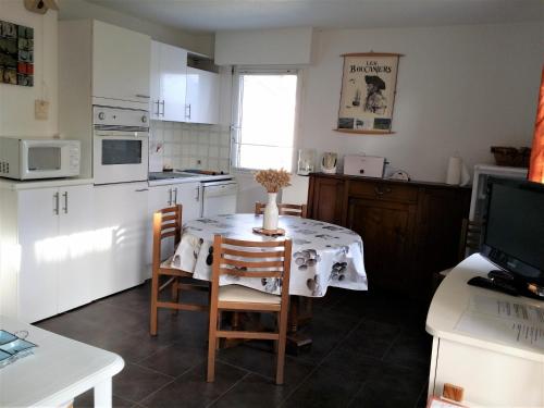 une cuisine avec une table et des chaises et une cuisine avec des armoires blanches dans l'établissement Apt 4 pers - 200 m de la plage - Terrasse - CONGARD, à Kervernoïs