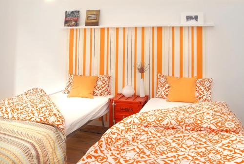 2 Betten in einem Zimmer mit orangefarbenen und gelben Streifen in der Unterkunft Düsselapp in Düsseldorf