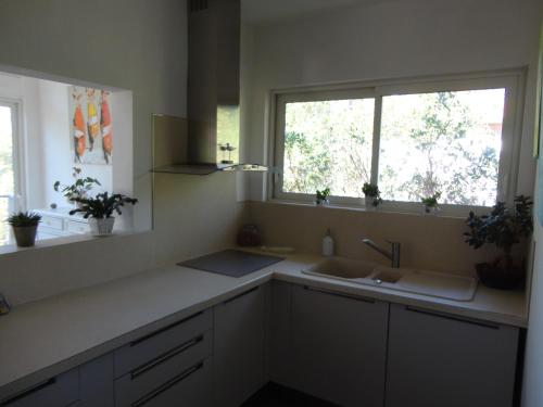 une cuisine avec deux lavabos et une fenêtre dans l'établissement une maison lumineuse sous les pins, à Le Canon