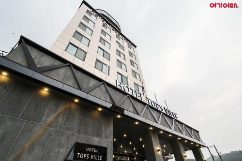 a tall hotel building with a sign on it at Hotel TopsVille in Gangneung