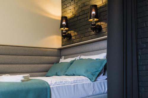 a bed with two lights on a brick wall at Apartamenty Wodna 13 in Poznań