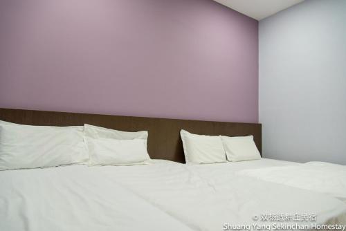 a large bed with white sheets and pillows at Shuang Yang Sekinchan Homestay in Sekincan