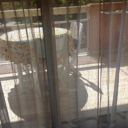 uma vista para um pátio através de uma janela de vidro em Cavalaire chez Michelle em Cavalaire-sur-Mer
