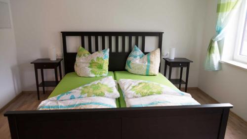 ein Bett mit zwei Kissen darauf und zwei Tischen in der Unterkunft Ferienwohnung Rennsteigblick in Tambach-Dietharz