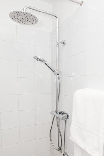 a shower in a bathroom with white tiles at Karlskoga Hotell & Konferens in Karlskoga