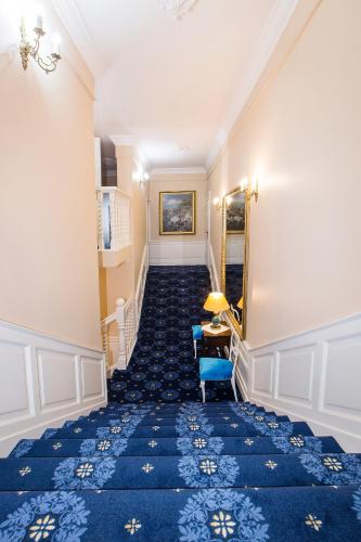a staircase with blue carpet and a blue chair at Dwór Hetman in Jarosław