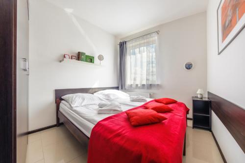 a bedroom with a bed with a red blanket on it at Apartamenty Sun & Snow Lisi Jar in Jastrzębia Góra