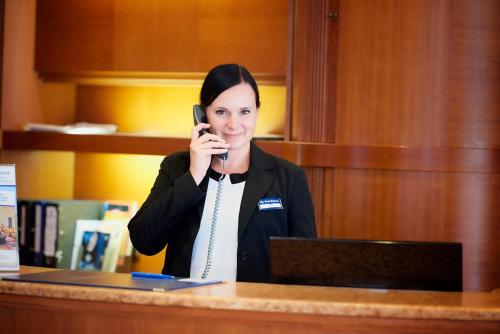 a woman talking on a phone in a kitchen at Best Western Hotel Leipzig City Centre in Leipzig