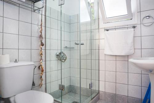 Maria's Garden Apartments في لاسي: حمام مع دش مع مرحاض ومغسلة