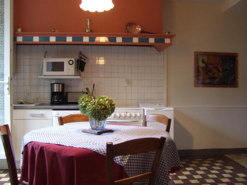 una cocina con una mesa con un jarrón de flores. en Gite chez Cyrano en Bergerac