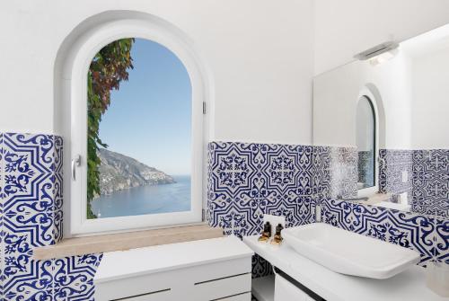a bathroom with blue and white tiles and a window at Hotel Le Agavi in Positano
