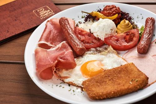 a plate of breakfast food with eggs sausage and tomatoes at Pansion Kamin in Sarajevo