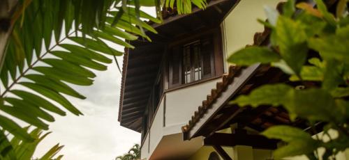 a building with a window and a palm tree at Pauba Praia Hotel in Pauba