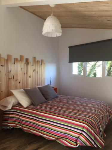 1 dormitorio con 1 cama grande con manta a rayas en Hostel Cañaveral, en Cañaveral