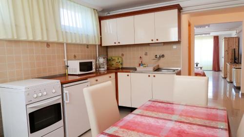 a kitchen with white appliances and white cabinets at Magyar Apartmanház IV. in Zalakaros