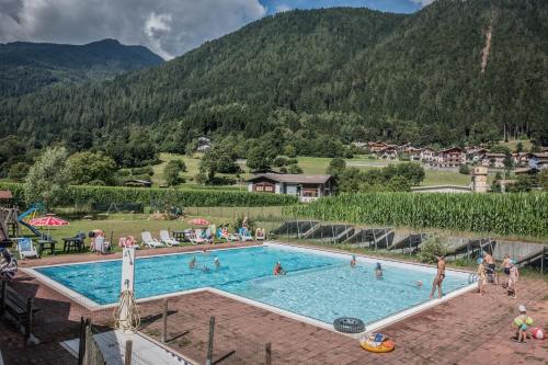a large pool with people in it with mountains in the background at Sarca Lodge Val Rendena in Dare